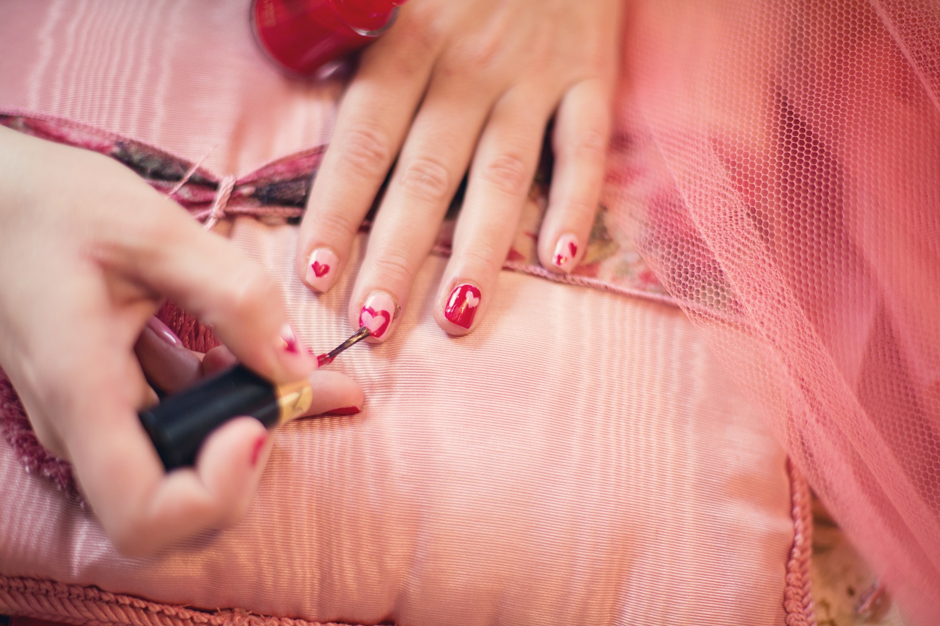 someone painting nailpolish pink background